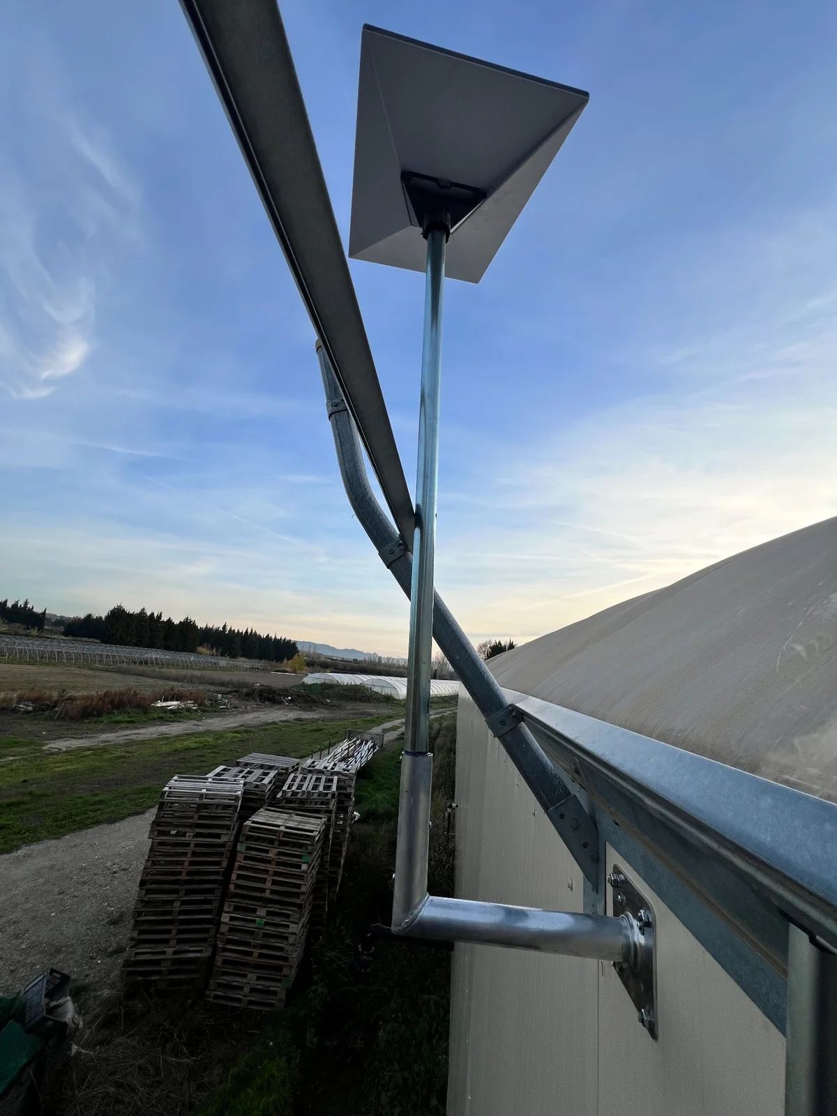 Détail du mât et du support de l’antenne Starlink à l’extérieur de la serre